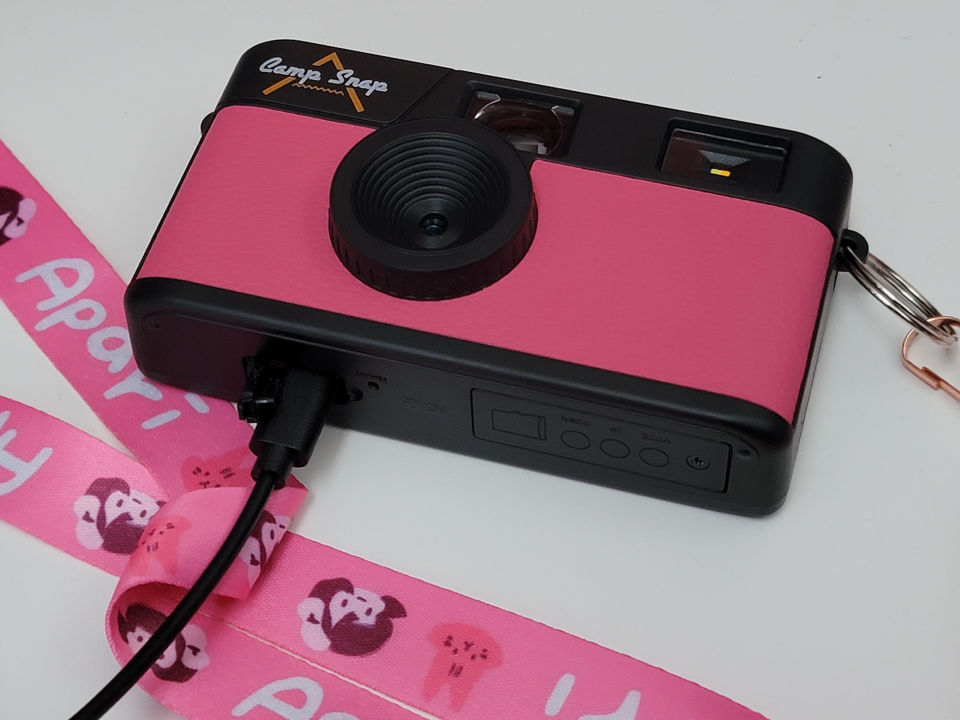 photo of a hot pink digital camera with a disposable vintage style design attached to a pink lanyard