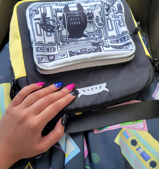 Close-up of skirt print, crossbody bag with monster subway illustration, and press-on nails.
