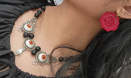 Close-up of oracle-themed necklace and red wax seal earrings.