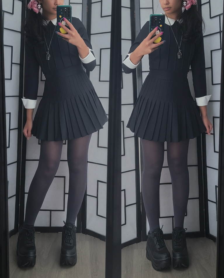 Dark academia style outfit with a black pleated dress with contrast cuffs and round collar.