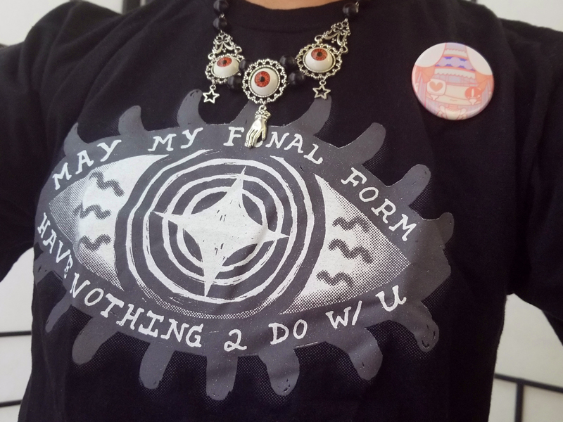 Shirt print details of a cartoon eye and the words ‘May my final form have nothing to do with you’.