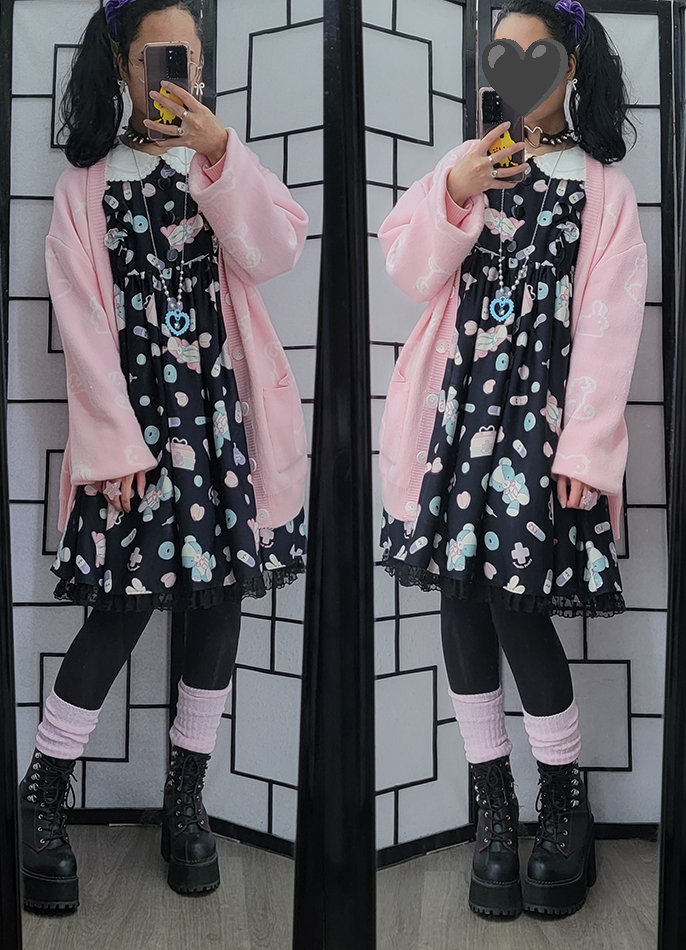 A casual lolita coordinate featuring a black menhera print dress and and oversized pastel pink cardigan.