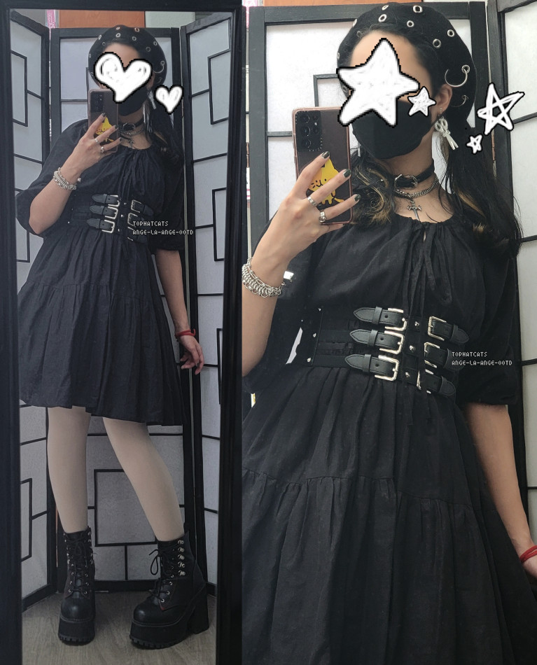 An all black outfit featuring a dress, belt corset, metal accessories, and a black face mask.