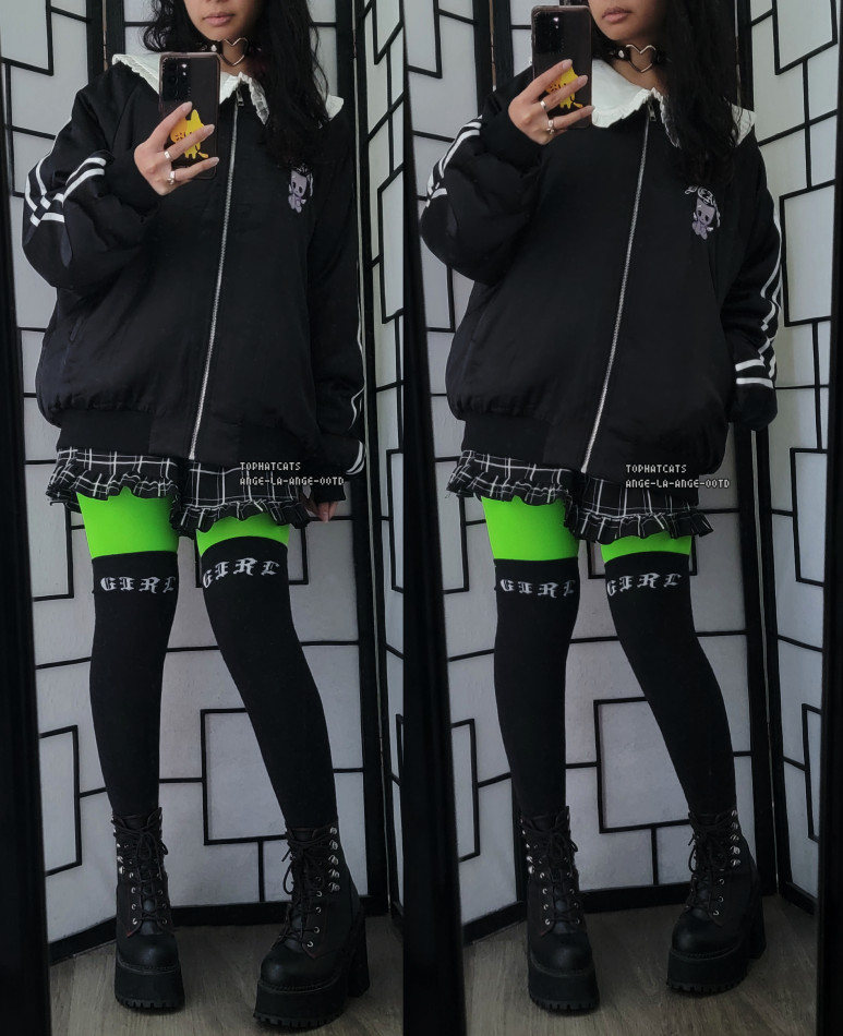 A mostly black outfit featuring an oversized sailor collar bomber jacket, plaid frilled shorts, neon green tights, and black OTKs.