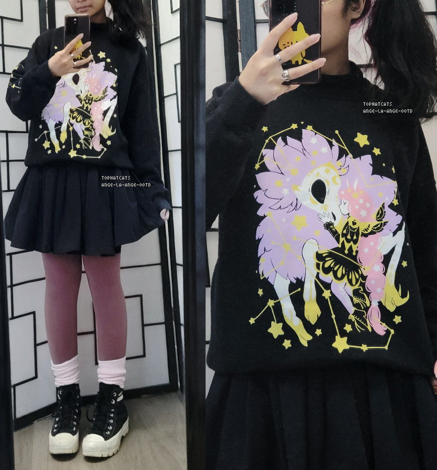 A black casual outfit featuring a constellation themed character and creature crewneck, navy pleated skirt, and scrunched loose socks layered over mauve tights.